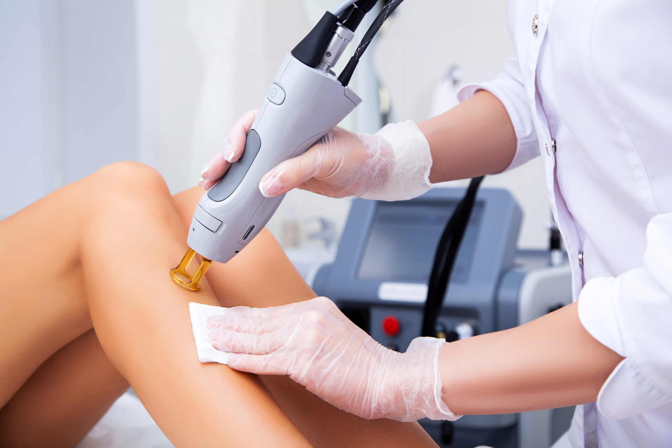 Close-up of a female cosmetologist in a medical coat making a yo laser hair removal
